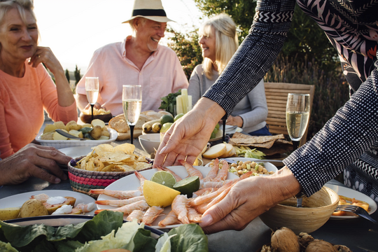 Familie genießt gemeinsames Essen. Frisches Gemüse, Fisch und Knoblauch - ideal für Herz und Kreislauf. 