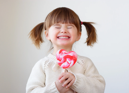 Kind mit großem Lolly in der Hand strahlt glücklich